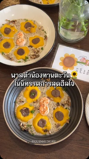 จานพาสต้าเส้นสดสีเหลืองสดใสรูปดอกทานตะวัน ราดด้วยซอสครีมทรัฟเฟิลเข้มข้น มีกุ้งตัวใหญ่สามตัวและสมุนไพรสีเขียวโรยหน้า ปักด้วยธงเล็กๆ มีข้อความว่า "NANPED" (แนนเพ็ด) พาสต้าจานนี้เป็นเมนูพิเศษสำหรับงาน Coming Heart Exhibition ของ Nanped ซึ่งจัดขึ้นที่ Narisa Cafe&Creative Space