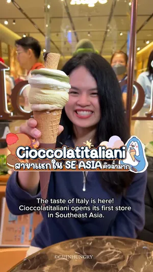 ภาพโคลสอัพไอศกรีมเจลาโตโคนใหญ่จากร้าน Cioccolatitaliani ที่มือหนึ่งกำลังถืออยู่ ไอศกรีมมีเนื้อเนียนนุ่มเป็นเกลียวหลายรสชาติผสมผสานกัน เช่น รสมิลค์ครีม วานิลลา และเฮเซลนัท ราดด้วยซอสพิสตาชิโอสีเขียวอ่อนและซอสช็อกโกแลตสีเข้ม โคนเป็นวาฟเฟิลสีน้ำตาลอ่อน ด้านบนมีข้อความซ้อนทับว่า 'Cioccolatitaliani' และ 'FIRST BRANCH SOUTH EAST ASIA' ซึ่งระบุว่านี่คือสาขาแรกของแบรนด์เจลาโตชื่อดังจากอิตาลีแห่งนี้ในเอเชียตะวันออกเฉียงใต้ ตั้งอยู่ที่ CentralWorld