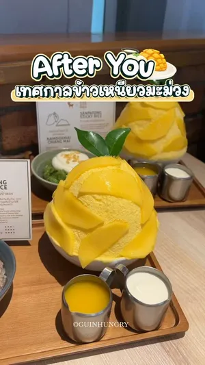 ภาพระยะใกล้ของเมนู "Mango sticky rice kakigōri" จาก After You Dessert Cafe ในชามสีขาว. น้ำแข็งไสละเอียดสีขาวราดด้วยเนื้อมะม่วงน้ำดอกไม้สุกสีเหลืองทองหั่นชิ้นสวยงาม วางเรียงรายคือข้าวเหนียวมูนสองชนิด ได้แก่ ข้าวเหนียวใบเตยสีเขียว และข้าวเหนียวงาขี้ม่อนสีม่วงอมน้ำตาล ซึ่งเป็นข้าวเหนียวพิเศษจากเชียงใหม่ที่ร่วมมือกับ Yudeemeesuk Mango Rice เสิร์ฟพร้อมเหยือกเล็กๆ บรรจุกะทิหรือซอส. เมนูนี้มีจำหน่ายเฉพาะ 6 สาขาที่ร่วมรายการ ราคา 325 บาท.