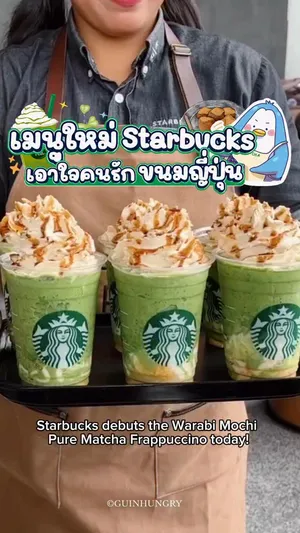 ภาพถ่ายเมนูใหม่ของ Starbucks (สตาร์บัคส์) ในการเปิดตัววันแรก แสดงเครื่องดื่ม Warabi Mochi Pure Matcha Cream Frappuccino ในแก้วใสของ Starbucks ขนาดกลาง ด้านบนเป็นวิปครีมสีขาว โรยหน้าด้วยผงคินาโกะสีน้ำตาลอ่อน และราดด้วยซอสคุโรมิสึสีเข้ม ตัวเครื่องดื่มเป็นมัทฉะสีเขียวสดใสปั่นรวมกับวาราบิโมจิหนึบหนับ วางอยู่บนโต๊ะไม้หรือพื้นผิวเรียบสีอ่อน ด้านข้างอาจมีขนม Starbucks green tea Éclair และ Warabi Mochi Kinako วางประกอบ ภาพสื่อถึงการเริ่มต้นจำหน่ายเมนูใหม่ที่ผสมผสานรสชาติญี่ปุ่นแท้ๆ