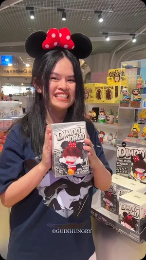 ภาพแสดงตู้โชว์สินค้าฟิกเกอร์อาร์ตทอย POP MART คอลเลกชัน DIMOO WORLD × DISNEY Series โดยมีฟิกเกอร์ DIMOO หลากหลายแบบที่แต่งกายเป็นตัวละครดิสนีย์ยอดนิยม เช่น มิกกี้เมาส์ มินนี่เมาส์ โดนัลด์ดั๊ก และกู๊ฟฟี่ จัดแสดงอย่างเป็นระเบียบและสว่างไสวภายในร้าน POP MART POP-UP ชั้น 1 เซ็นทรัลเวิลด์ ซึ่งเป็นการเปิดจำหน่ายวันแรกของคอลเลกชันนี้ มีข้อความซ้อนทับว่า "DIMOO WORLD" และ "DISNEY"