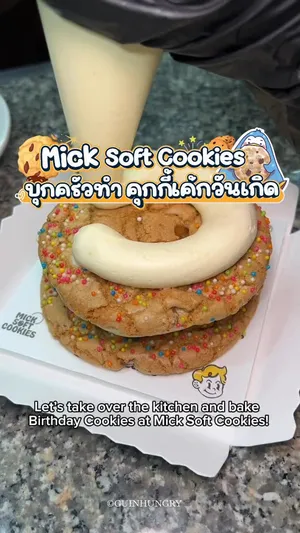 ภาพมือสองข้างกำลังถือคุกกี้เค้กทรงกลมขนาดใหญ่ที่ตกแต่งด้วยสปริงเคิลและครีมชีสยูซุ จากร้าน @mick_soft_cookies ซึ่งคือเมนู "Birthday cookies (429)" ที่มีส่วนผสมของวอลนัท, บิสคอฟ, ช็อกโกแลต, เนยถั่วและมาร์ชเมลโลว์ ถัดไปมีคุกกี้ชิ้นเล็กเมนู "Golden Tea Break (75)" รสเอิร์ลเกรย์ที่ทำจากใบชา 2 ชนิด ผสมกับคอร์นเฟลกคาราเมลและอัลมอนด์ พร้อมเครื่องดื่มวางอยู่บนพื้นผิวสีอ่อน ข้อความบนภาพระบุว่า "Birthday cookies (429)", "Golden Tea Break (75)" และ "Yuzu cream cheese" ซึ่งเป็นรายละเอียดส่วนประกอบสำคัญของเมนู