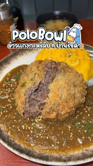 ภาพระยะใกล้ของชามข้าวแกงกะหรี่เนื้อคัตสึไข่ข้นจากร้าน Polo Bowl ย่านรัชดา เนื้อคัตสึชิ้นหนาทอดสีทองกรอบวางอยู่บนข้าวสวยร้อนๆ ราดด้วยแกงกะหรี่สไตล์โฮมเมดสีน้ำตาลเข้มและไข่ข้นสีเหลืองทองเยิ้มๆ มีเครื่องเคียงสีแดงเล็กน้อยบนจาน มีข้อความซ้อนทับบนภาพว่า "Polo Bowl", "Curry Rice", "ข้าวแกงกะหรี่เนื้อคัตสึไข่ข้น 169-" และ "อร่อยมากกกก"